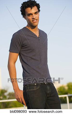 Stock Image - Smiling mixed race man standing outdoors. Fotosearch