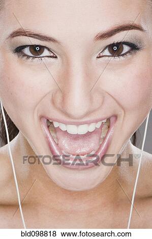 Stock Photo - Smiling mixed race woman listening to headphones. Fotosearch