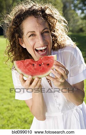 Stock Image - Smiling woman eating watermelon. Fotosearch
