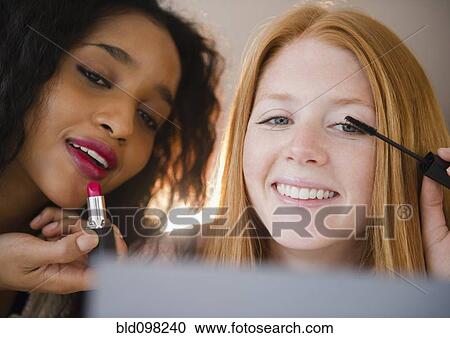 Stock Image - Smiling woman putting on makeup. Fotosearch