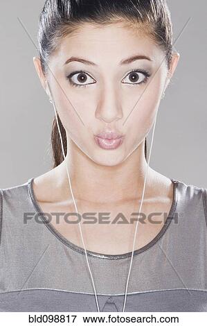 Stock Photo - Surprised mixed race woman listening to headphones. Fotosearch