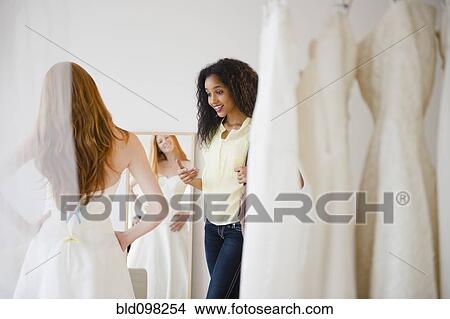 Woman helping friend try on wedding dress View Large Photo Image Picture - Woman helping friend try on wedding dress. Fotosearch