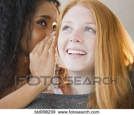 Woman whispering in friend's ear View Large Photo Image Stock Photo - Woman whispering in friend's ear. Fotosearch