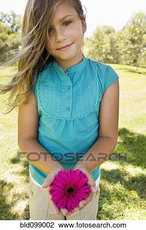 Stock Image - Young girl holding pink flower. Fotosearch
