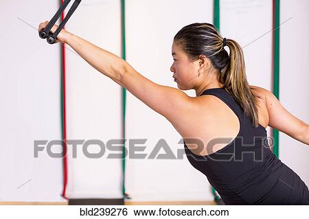 Stock Photograph - Asian woman holding handle in gymnasium. Fotosearch