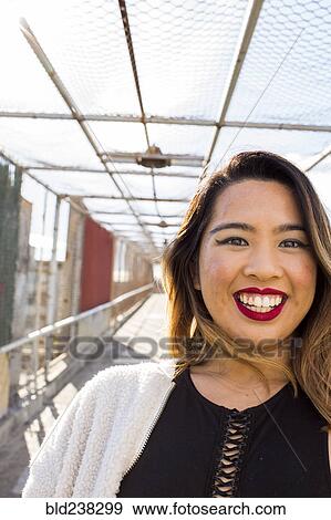 Asian woman smiling on footbridge View Large Photo Image Stock Photo - Asian woman smiling on footbridge. Fotosearch