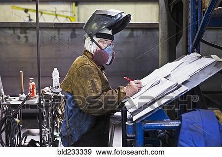 Asian worker wearing mask writing on paperwork in factory View Large Photo Image Stock Photo - Asian worker wearing mask writing on paperwork in factory. Fotosearch