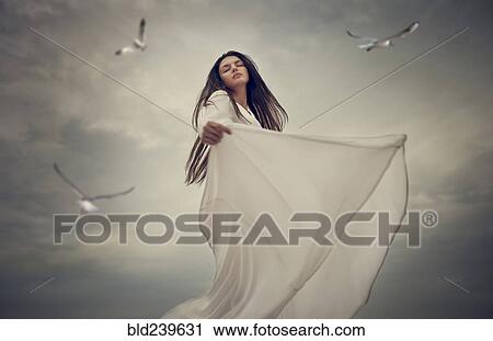 Stock Image - Birds flying near dancing Caucasian woman . Fotosearch