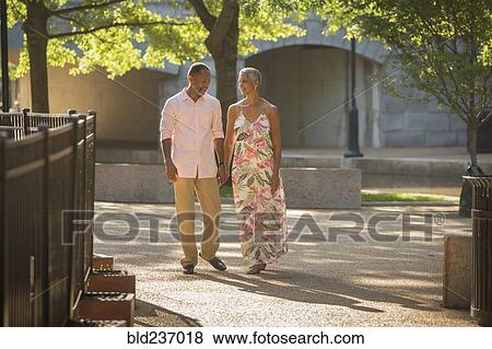 Black couple holding hands walking in park View Large Photo Image Stock Photo - Black couple holding hands walking in park. Fotosearch