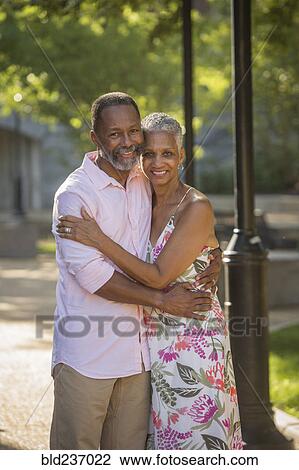 Stock Image - Black couple hugging in park. Fotosearch