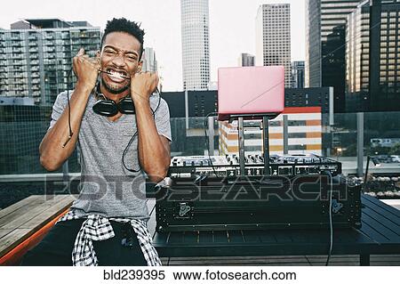 Black DJ biting headphones cord on urban rooftop View Large Photo Image Stock Photography - Black DJ biting headphones cord on urban rooftop. Fotosearch