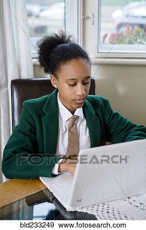 Stock Photo - Black girl wearing school uniform using laptop. Fotosearch