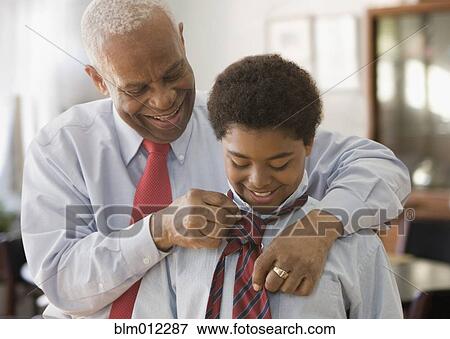 Stock Photo - Black grandfather tying grandson's necktie. Fotosearch