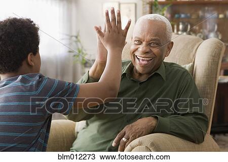 Stock Image - Black grandson high-fiving with grandfather. Fotosearch