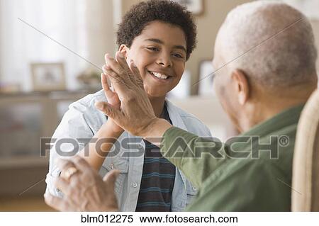 Stock Photography - Black grandson high-fiving with grandfather. Fotosearch