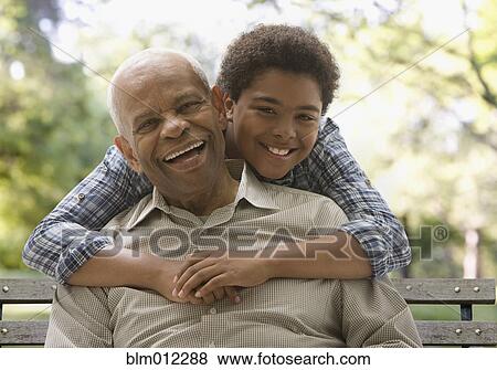 Black grandson hugging grandfather in park View Large Photo Image Stock Photo - Black grandson hugging grandfather in park. Fotosearch
