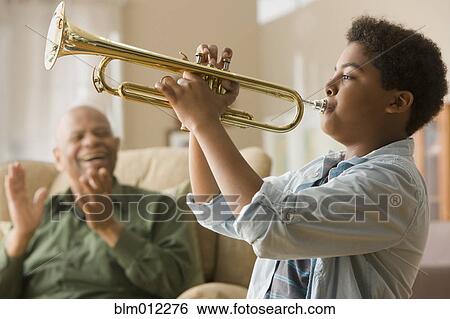 Stock Photograph - Black grandson playing trumpet for grandfather. Fotosearch