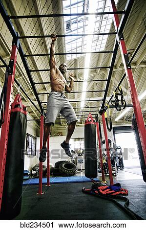 Black man hanging from bars in gymnasium View Large Photo Image Stock Image - Black man hanging from bars in gymnasium. Fotosearch