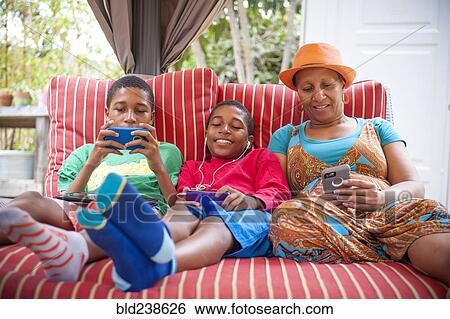 Black mother and twin sons using cell phones outdoors View Large Photo Image Stock Photograph - Black mother and twin sons using cell phones outdoors. Fotosearch