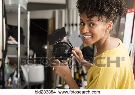 Picture - Black photographer adjusting lamp in studio. Fotosearch