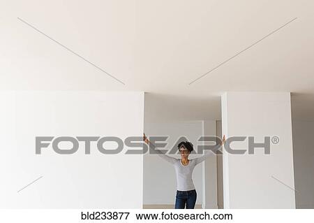 Stock Photo - Black woman leaning in doorway in empty apartment. Fotosearch