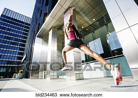 Black woman running and jumping on city sidewalk View Large Photo Image Stock Image - Black woman running and jumping on city sidewalk. Fotosearch