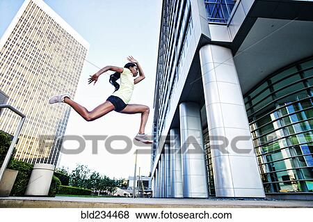 Stock Photo - Black woman running and jumping on city sidewalk. Fotosearch