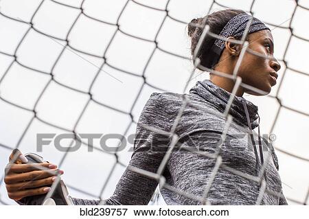 Black woman stretching leg behind chain-link fence View Large Photo Image Stock Photo - Black woman stretching leg behind chain-link fence. Fotosearch