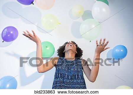Stock Image - Black woman watching falling balloons. Fotosearch