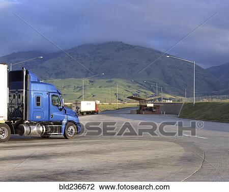 Stock Image - Blue semi-truck following arrows on road. Fotosearch
