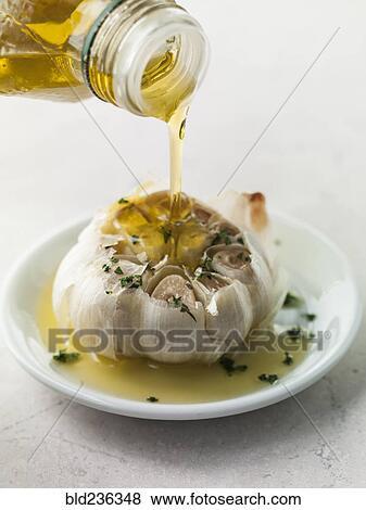 Bottle pouring olive oil on roasted garlic View Large Photo Image Stock Photo - Bottle pouring olive oil on roasted garlic. Fotosearch