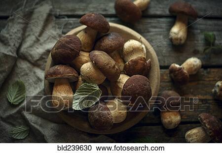 Stock Image - Bowl of mushrooms on wooden table. Fotosearch