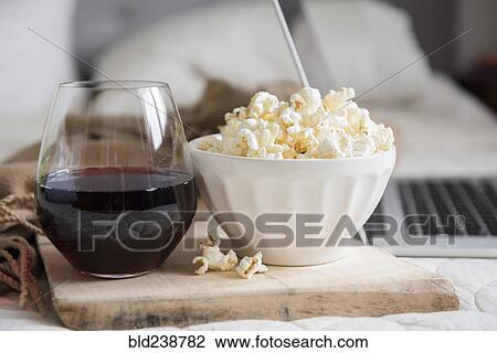 Bowl of popcorn and glass of wine near laptop View Large Photo Image Stock Image - Bowl of popcorn and glass of wine near laptop. Fotosearch