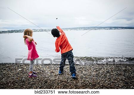 Boy and girl throwing rocks into river View Large Photo Image Stock Image - Boy and girl throwing rocks into river. Fotosearch