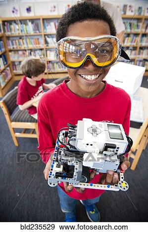 Stock Photo - Boy wearing goggles posing with plastic blocks in library. Fotosearch