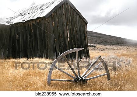 Stock Photography - Broken wooden wheel in grass near rustic building. Fotosearch