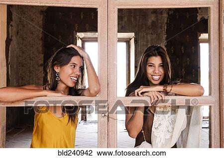 Stock Image - Brunette women leaning on windowless doors. Fotosearch