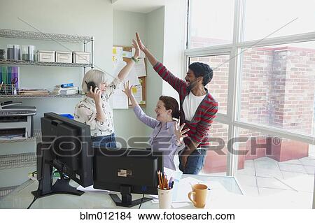 Business people high-fiving in office View Large Photo Image Picture - Business people high-fiving in office. Fotosearch
