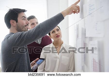 Business people talking about paperwork on wall View Large Photo Image Stock Image - Business people talking about paperwork on wall. Fotosearch