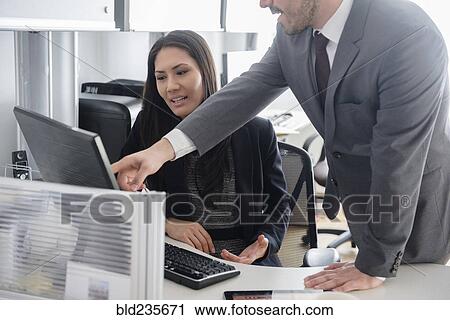 Stock Image - Business people talking in office using computer. Fotosearch