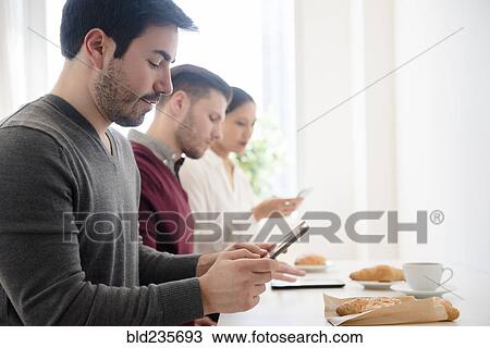 Business people using technology at breakfast table View Large Photo Image Stock Image - Business people using technology at breakfast table. Fotosearch