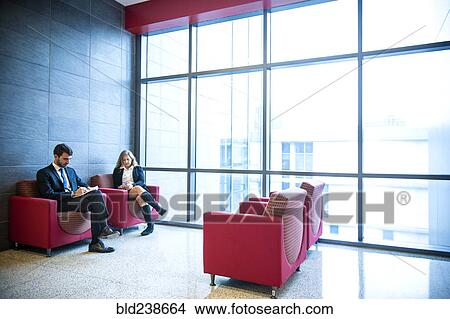 Picture - Businessman and businesswoman sitting in office lounge. Fotosearch