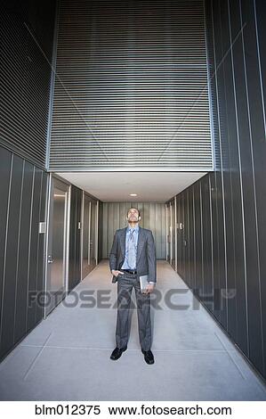 Stock Photography - Businessman holding digital tablet in corridor. Fotosearch