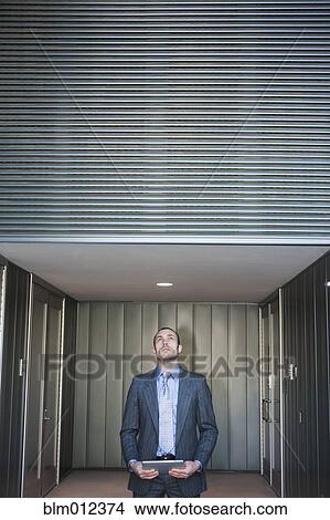Picture - Businessman using digital tablet in corridor. Fotosearch