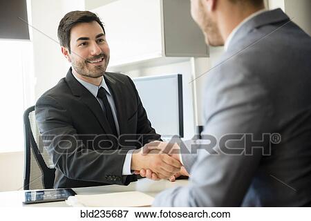 Businessmen shaking hands in office View Large Photo Image Stock Photo - Businessmen shaking hands in office. Fotosearch