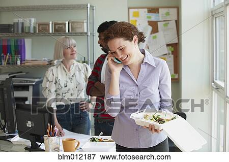 Businesswoman holding lunch and talking on telephone View Large Photo Image Stock Photo - Businesswoman holding lunch and talking on telephone. Fotosearch