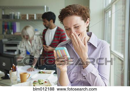 Stock Photo - Businesswoman laughing at text message. Fotosearch