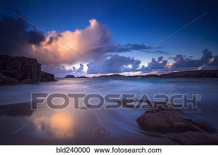 Stock Image - Calm waves on beach at sunset. Fotosearch