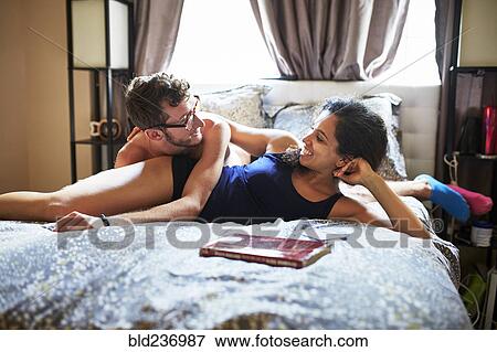 Stock Photo - Carefree couple relaxing on bed. Fotosearch
