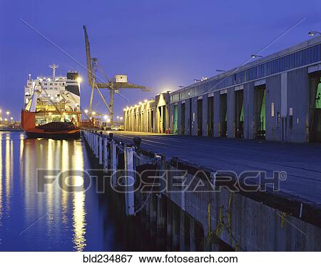 Cargo ship under crane in harbor at night View Large Photo Image Stock Photo - Cargo ship under crane in harbor at night. Fotosearch